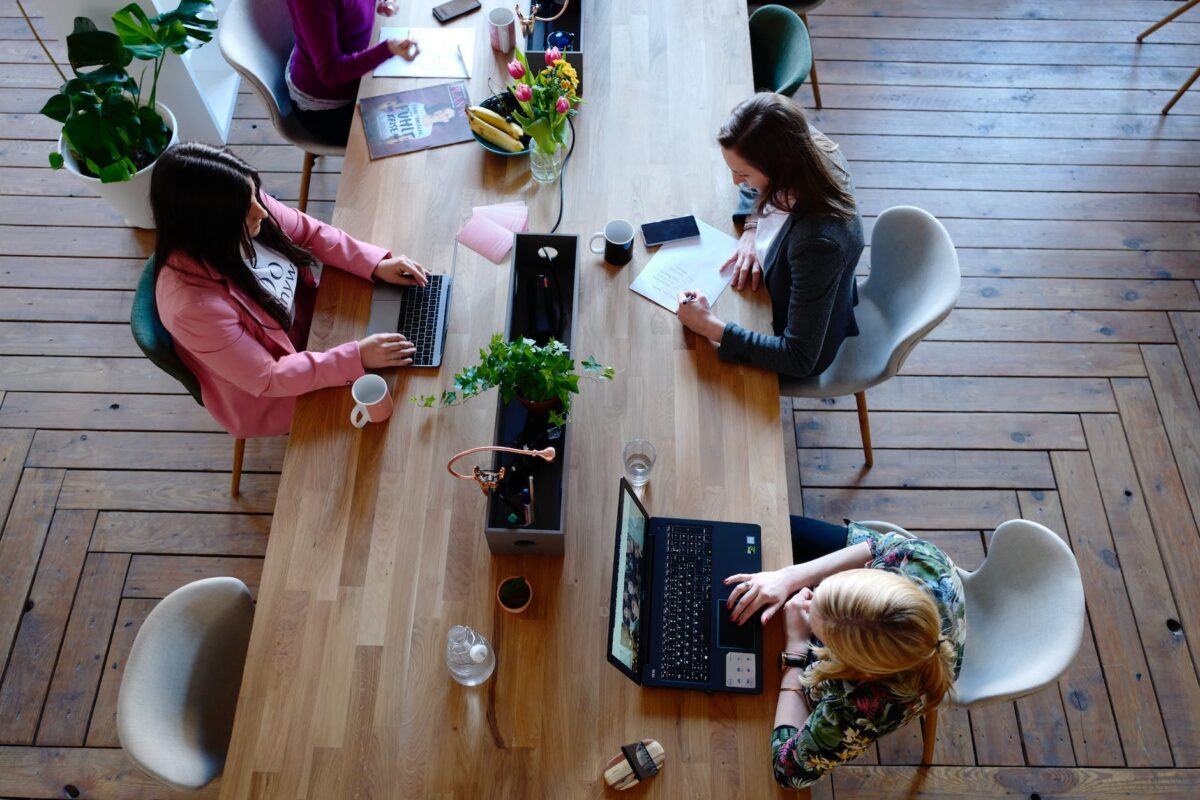 Three woman sitting on white chair in front of table. Loads4Less Business Removals Customer Staff Photograph