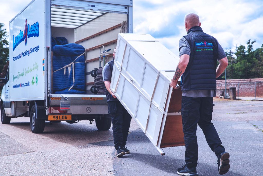 Two men carrying secured wardrobe. Man with a van furniture demonstration.